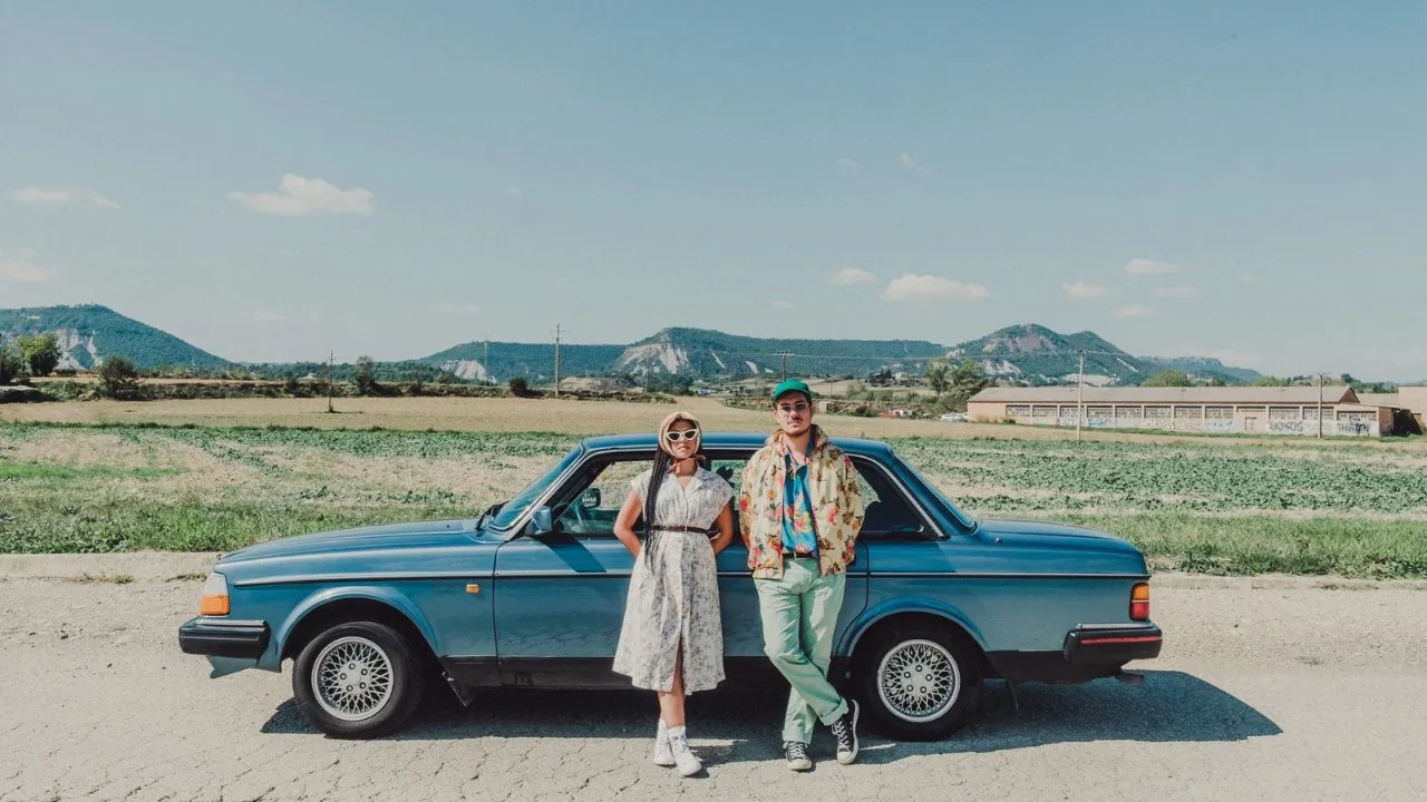Man and woman standing side by side against a car