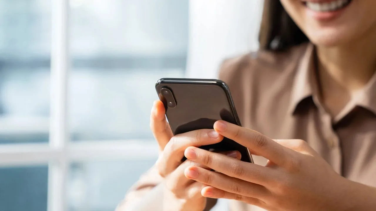 A woman smiling at something on her phone