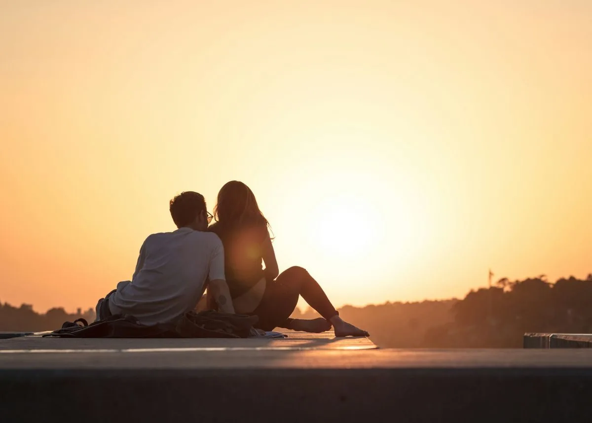 man and woman watching the sun set
