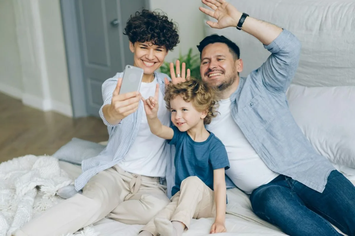 a father, mother and child taking selfie on the bed