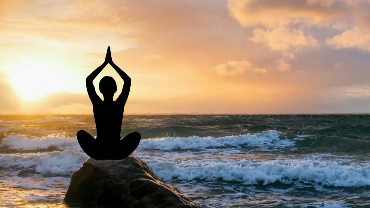 a figure doing yoga close to an ocean