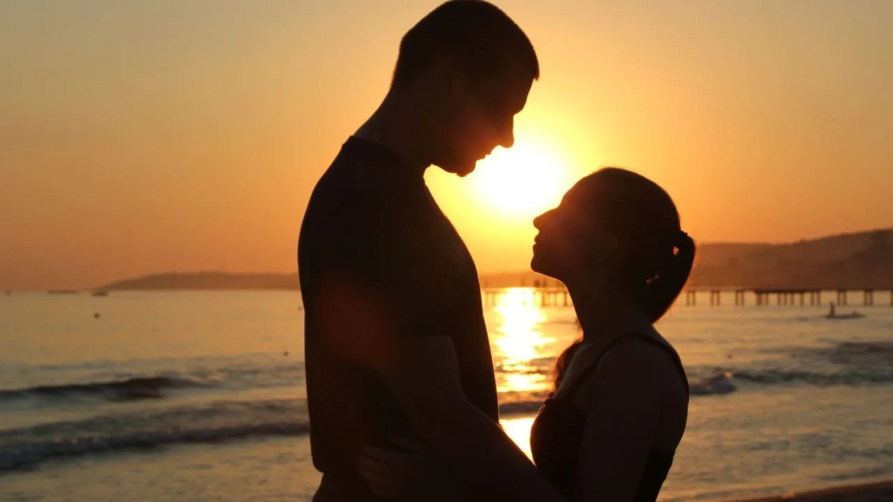 Silhouette of a man and woman against a sunset backdrop