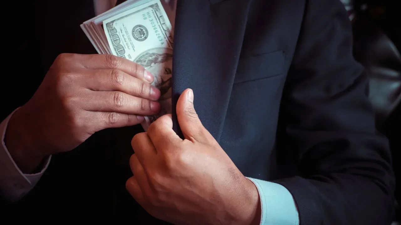 Man placing a wand of dollar bills into his suit pocket